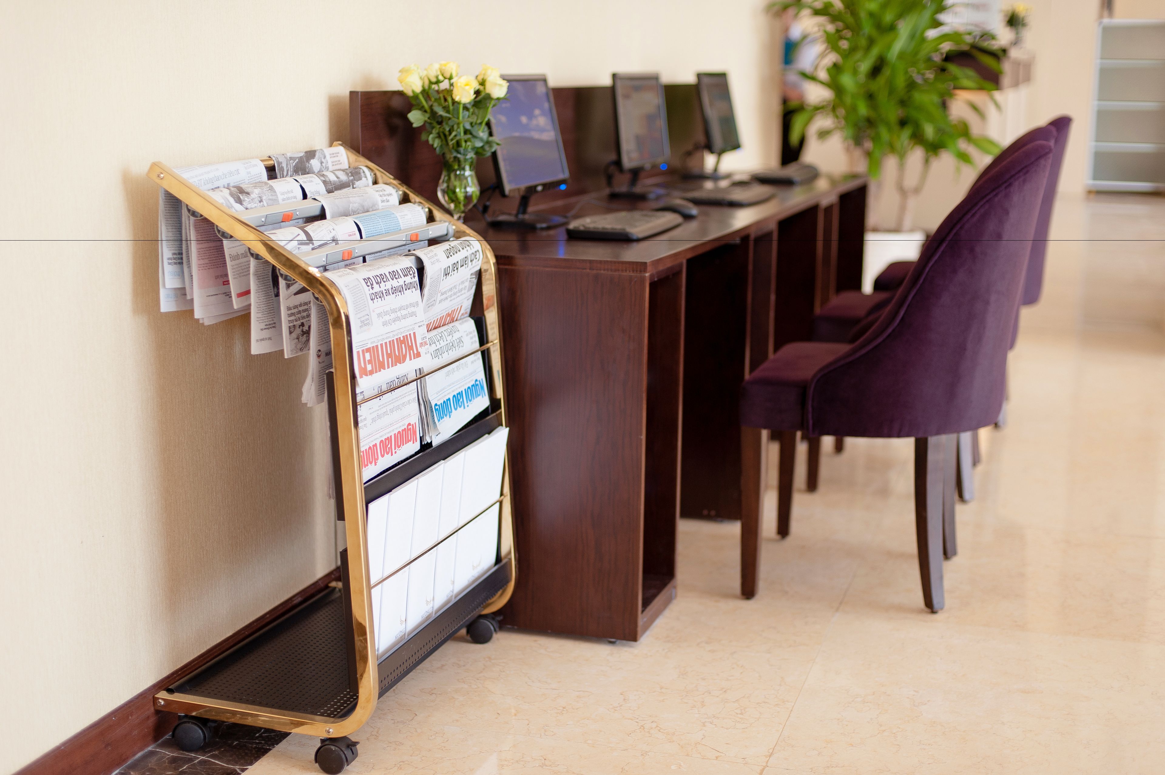 A reception desk with a newspaper cart, multiple computer monitors, and a purple chair.