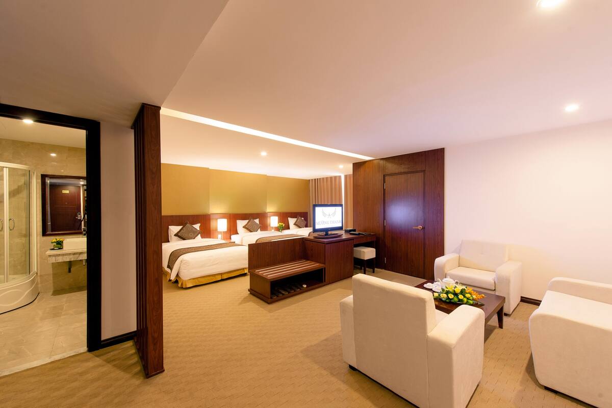 A hotel room with a bed, a desk, a TV, a sofa, and a coffee table.