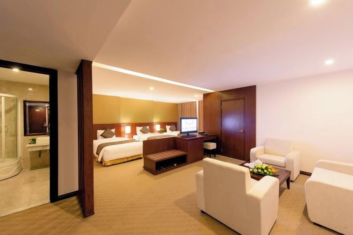 Una habitación de hotel con una cama, un escritorio con computadora, un sofá y una mesa de centro.