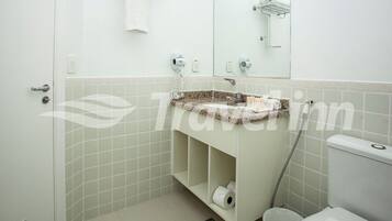 Un baño con lavamanos, inodoro y perchero para toallas.