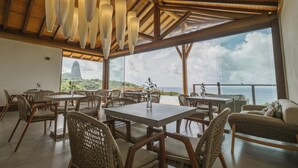 A restaurant with wicker furniture and a view of the ocean. - Colina Pousada SPA (Fernando de Noronha)