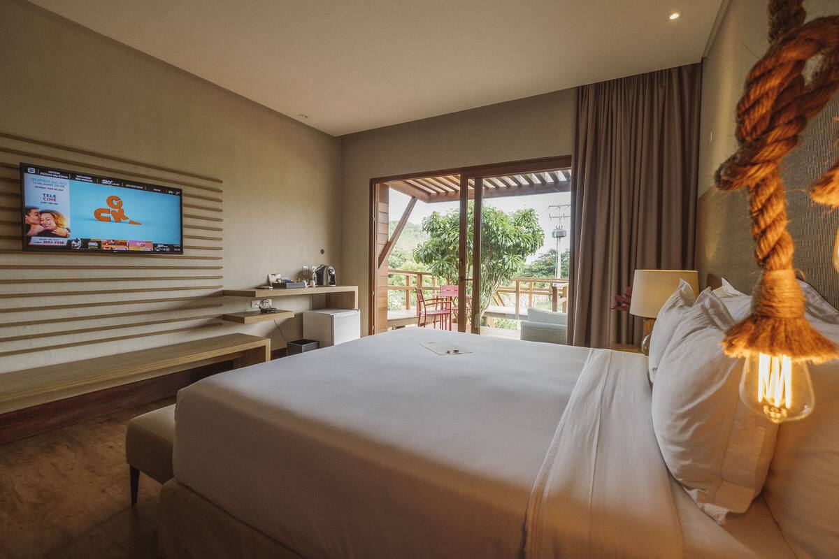 Une chambre d’hôtel avec un grand lit, un téléviseur fixé au mur, un bureau et une vue sur l’extérieur.