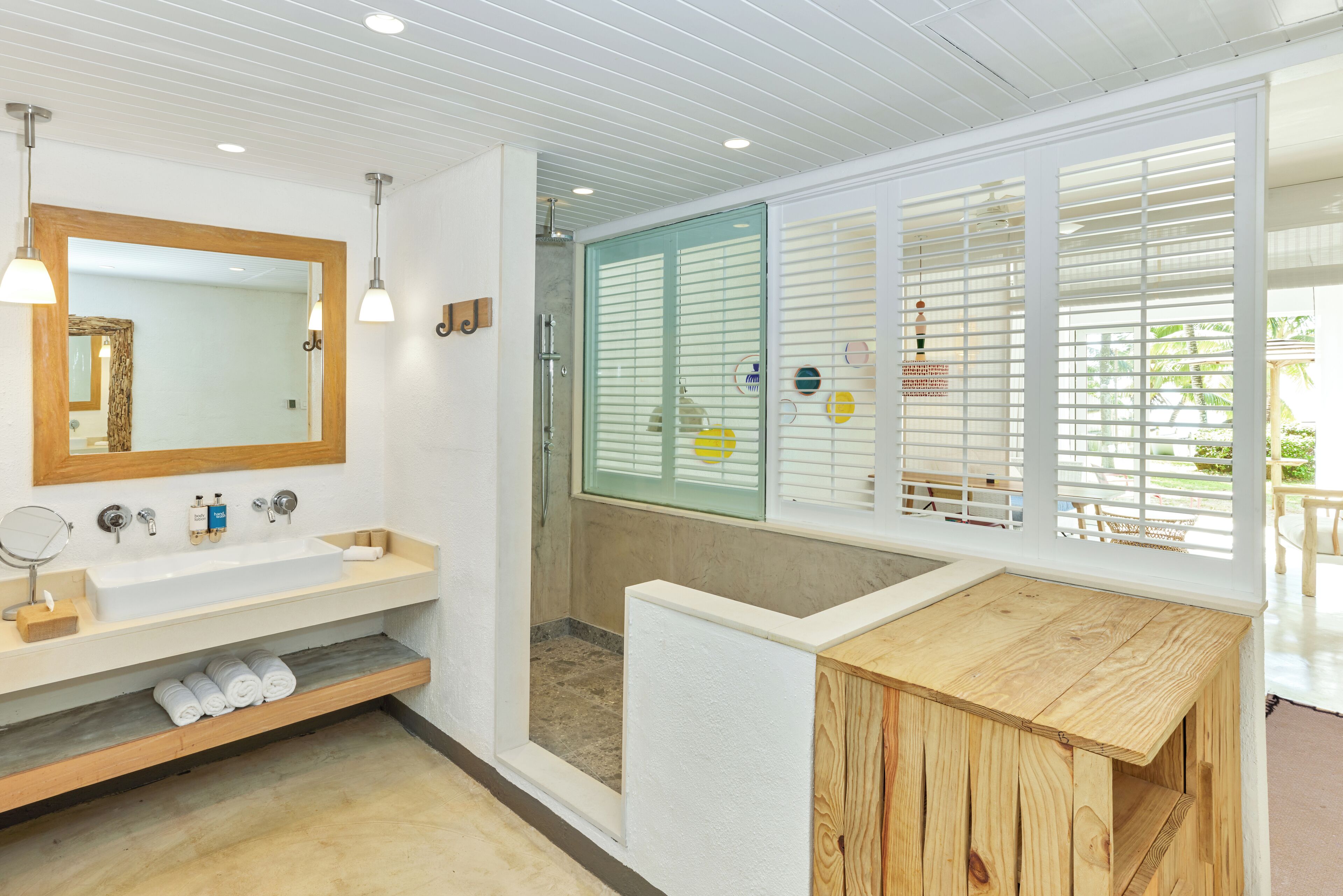 Een moderne badkamer met een grote spiegel, een houten wastafelmeubel en een douche met ruitverdelde glazen deuren.