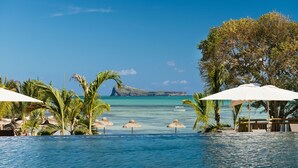 A clear view of an infinity pool with a view of the ocean and a distant island. - Zilwa Attitude (Calodyne)