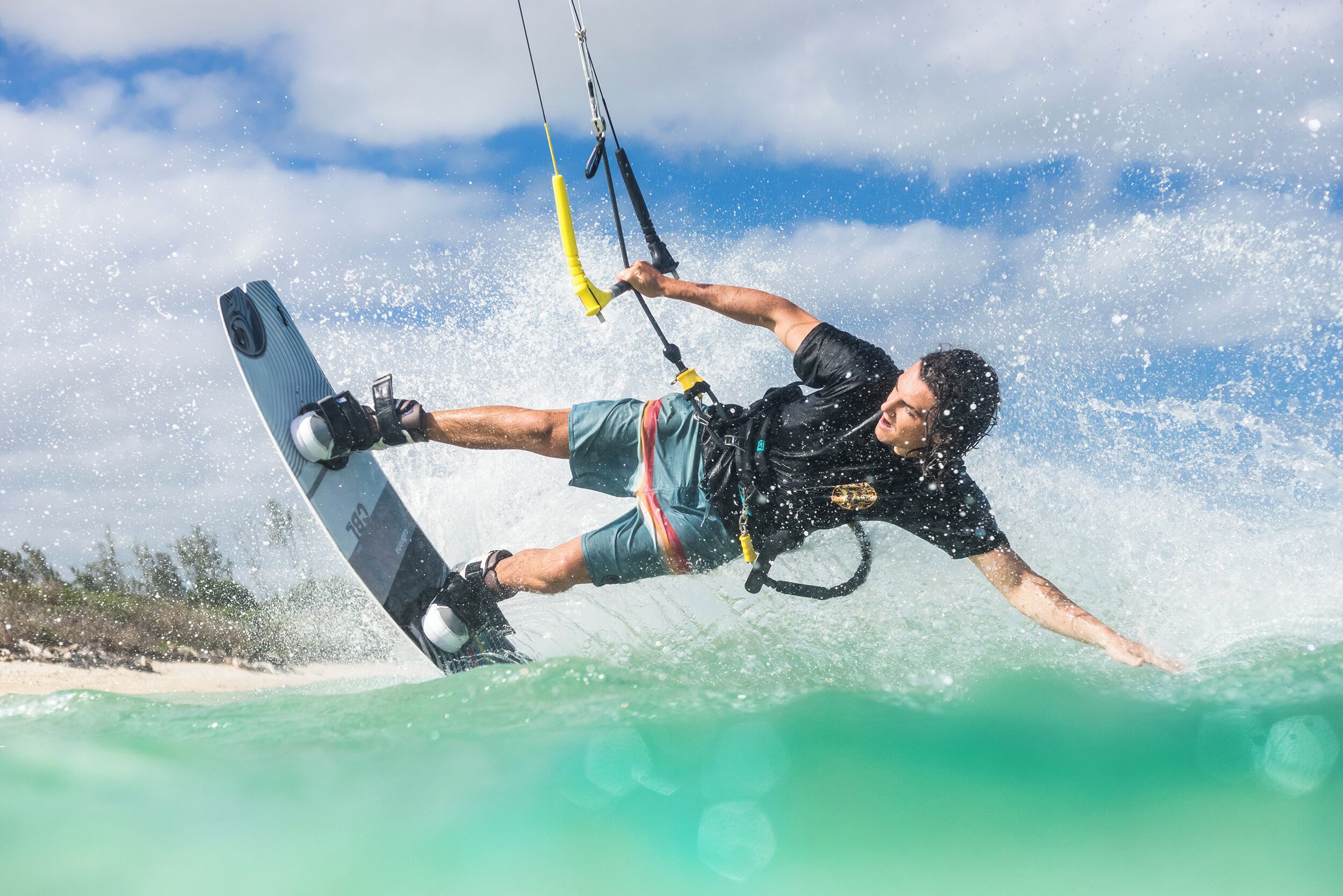 Une personne pratiquant le kitesurf sur une eau turquoise, avec un ciel dégagé en arrière-plan.