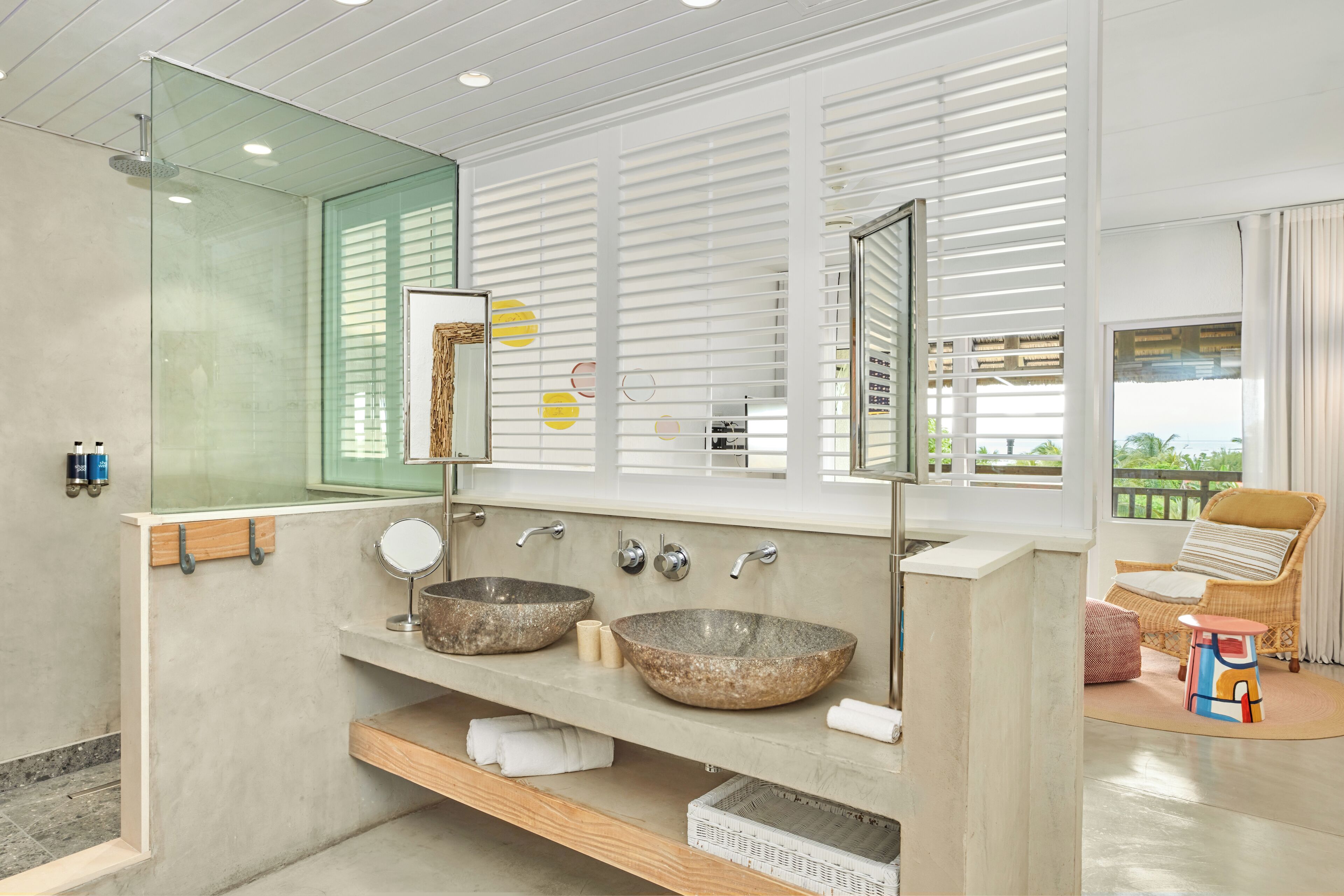 Ein modernes Badezimmer mit zwei großen Steinswaschbecken, einem großen Spiegel und einer Duschkabine aus Glas.