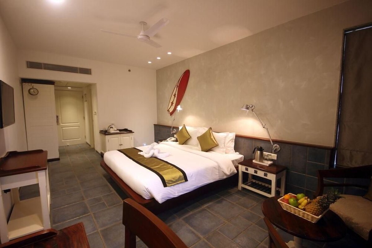 A hotel room with a bed, bedside table, lamp, and a fruit basket.
