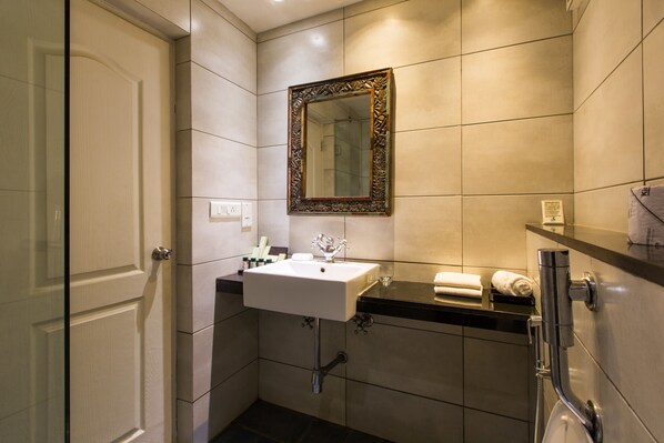 A modern bathroom with a white sink, a mirror with an ornate frame, and a shower area. - The Fern Residency Miramar (Panaji)