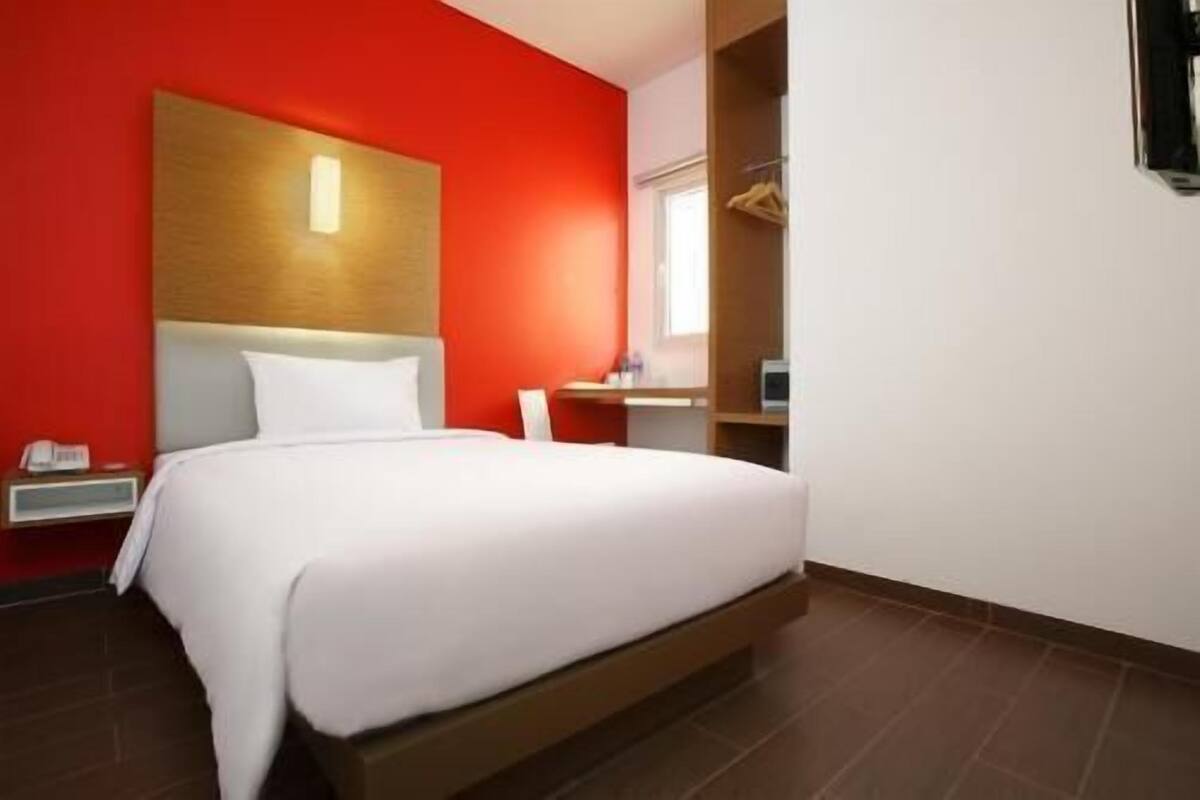 Una habitación de hotel con cama, mesita de noche, escritorio y armario.