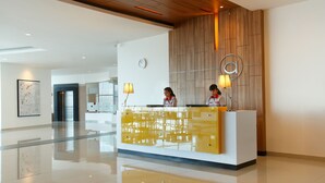 Un mostrador de recepción moderno con cubierta de vidrio y un panel de pared de madera detrás.
