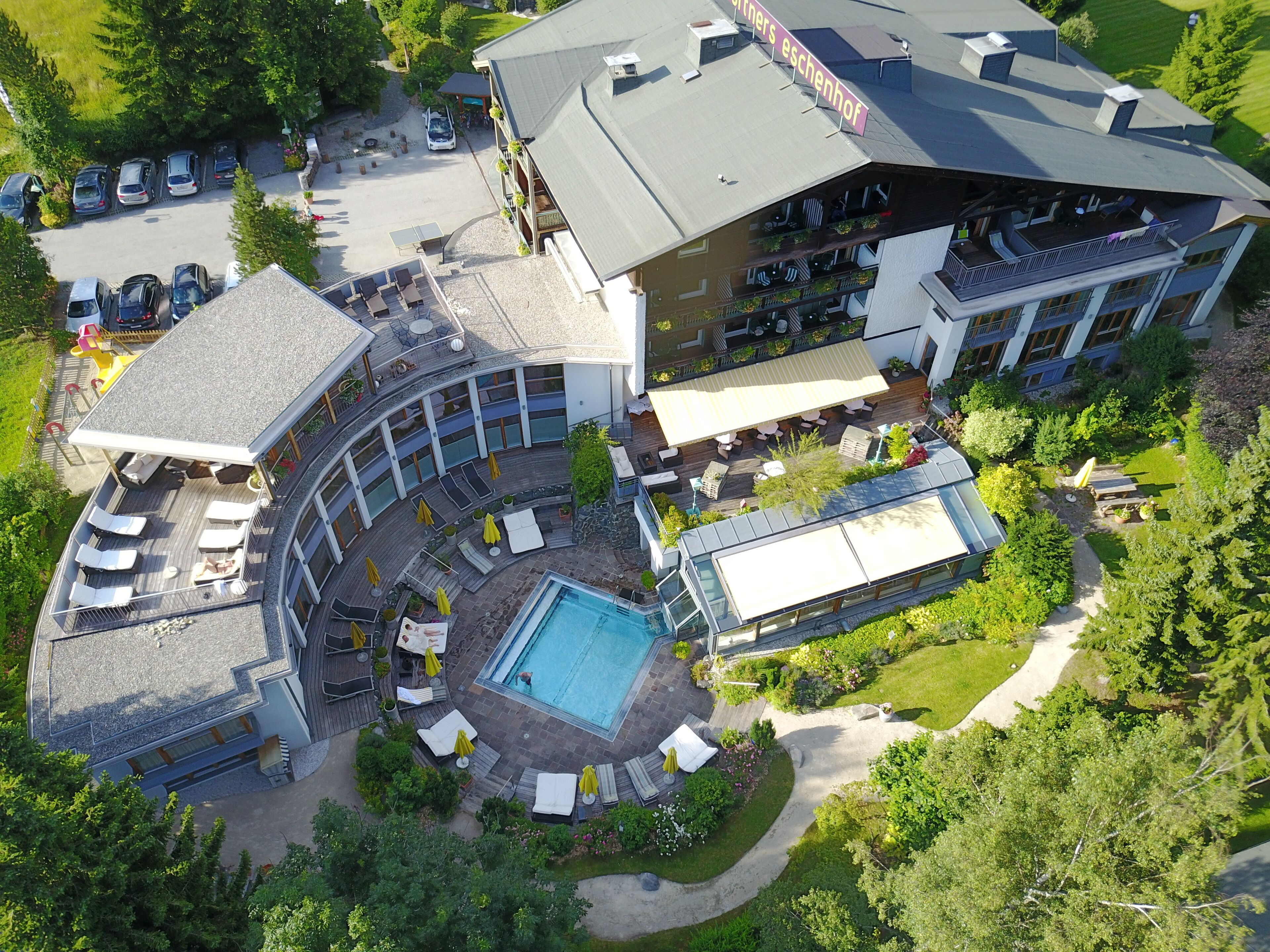 Ein mehrstöckiges Hotel mit Pool, Außenbereich zum Sitzen und einer überdachten Terrasse.