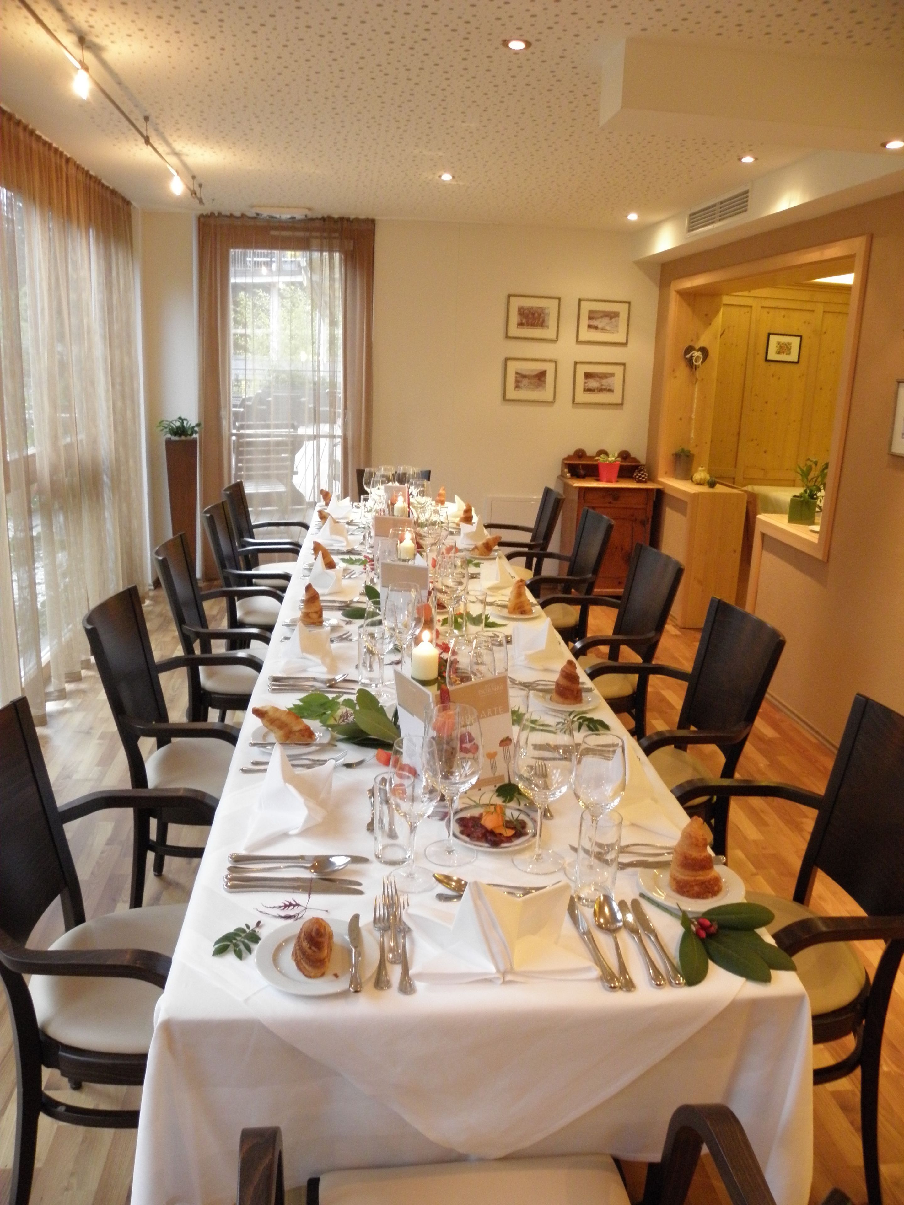 Una larga mesa de comedor con sillas, velas y vajilla.