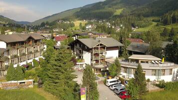 A mountain resort with chalet-style buildings, a parking area, and a view of the surrounding forest and hills.