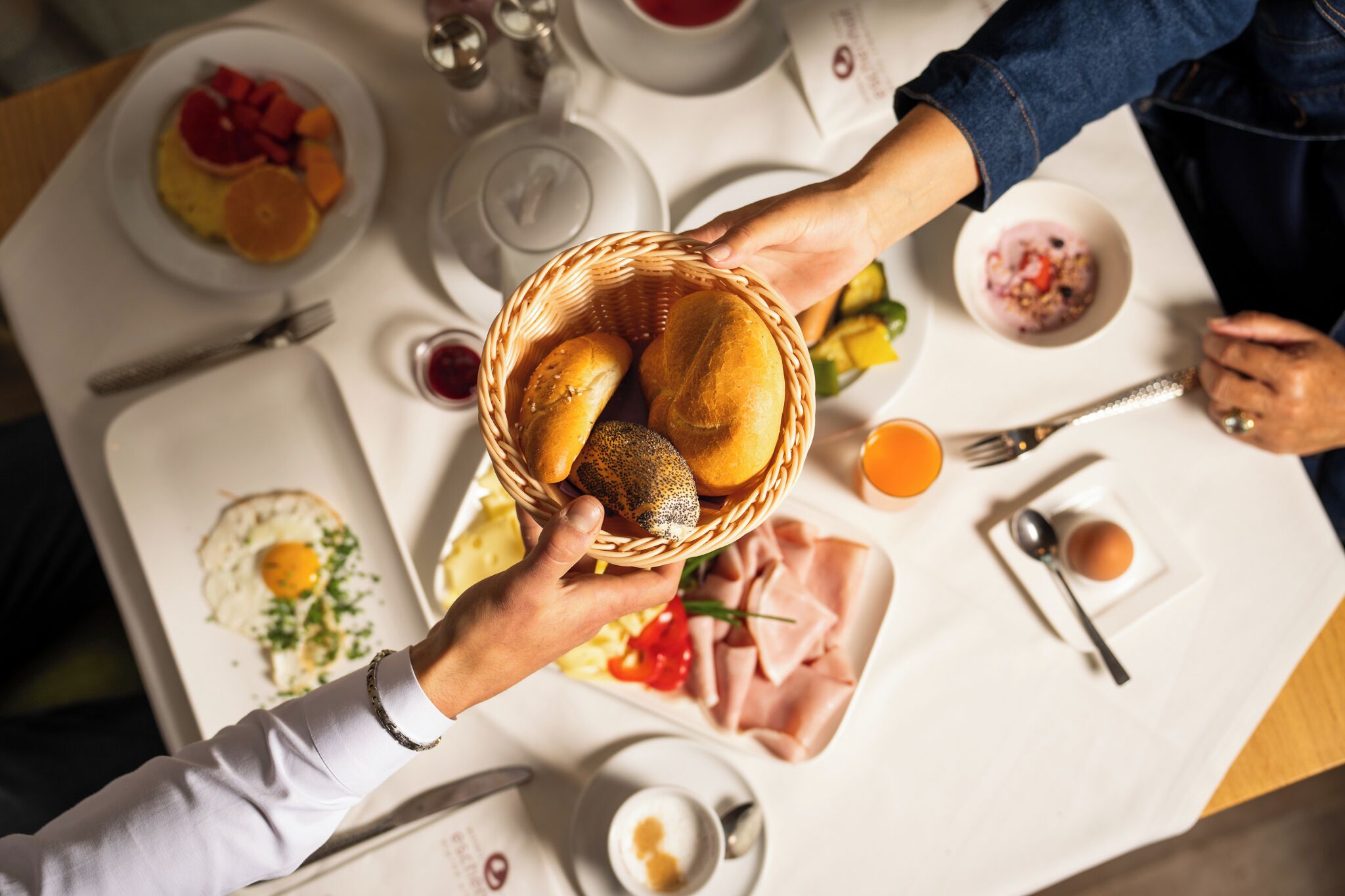 Un tavolo da pranzo con piatti di cibo, un cesto di pane e posate.
