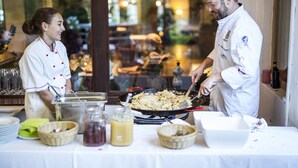 Un chef preparando comida en una cocina con una mesa lista para comer, incluyendo platos, tazones y una jarras de bebidas.