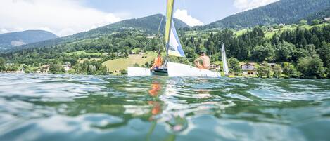 Un velero en un lago, con un paisaje montañoso al fondo.