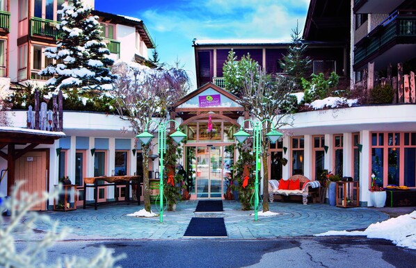A hotel entrance with a snow-covered pathway, a central entrance, and a sign above the door. - Hotel Eschenhof (Bad Kleinkirchheim)