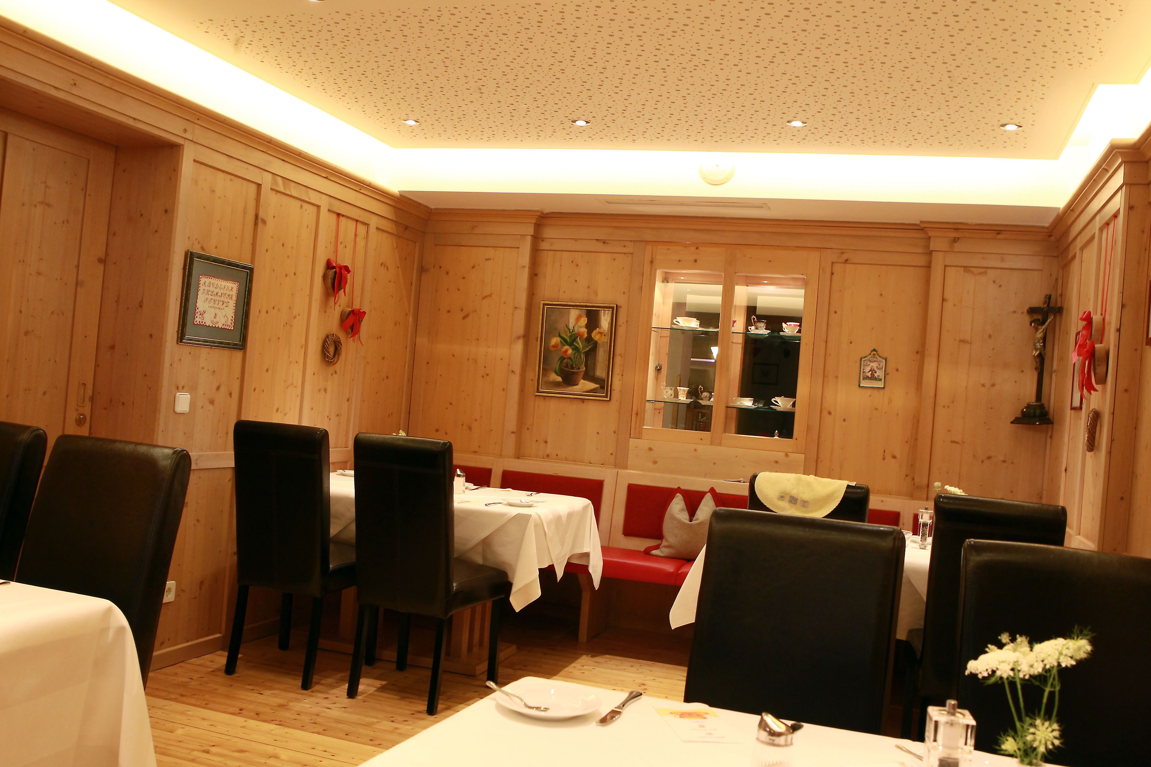 Een restaurant met houten lambrisering, witte tafellakens en zwarte stoelen.