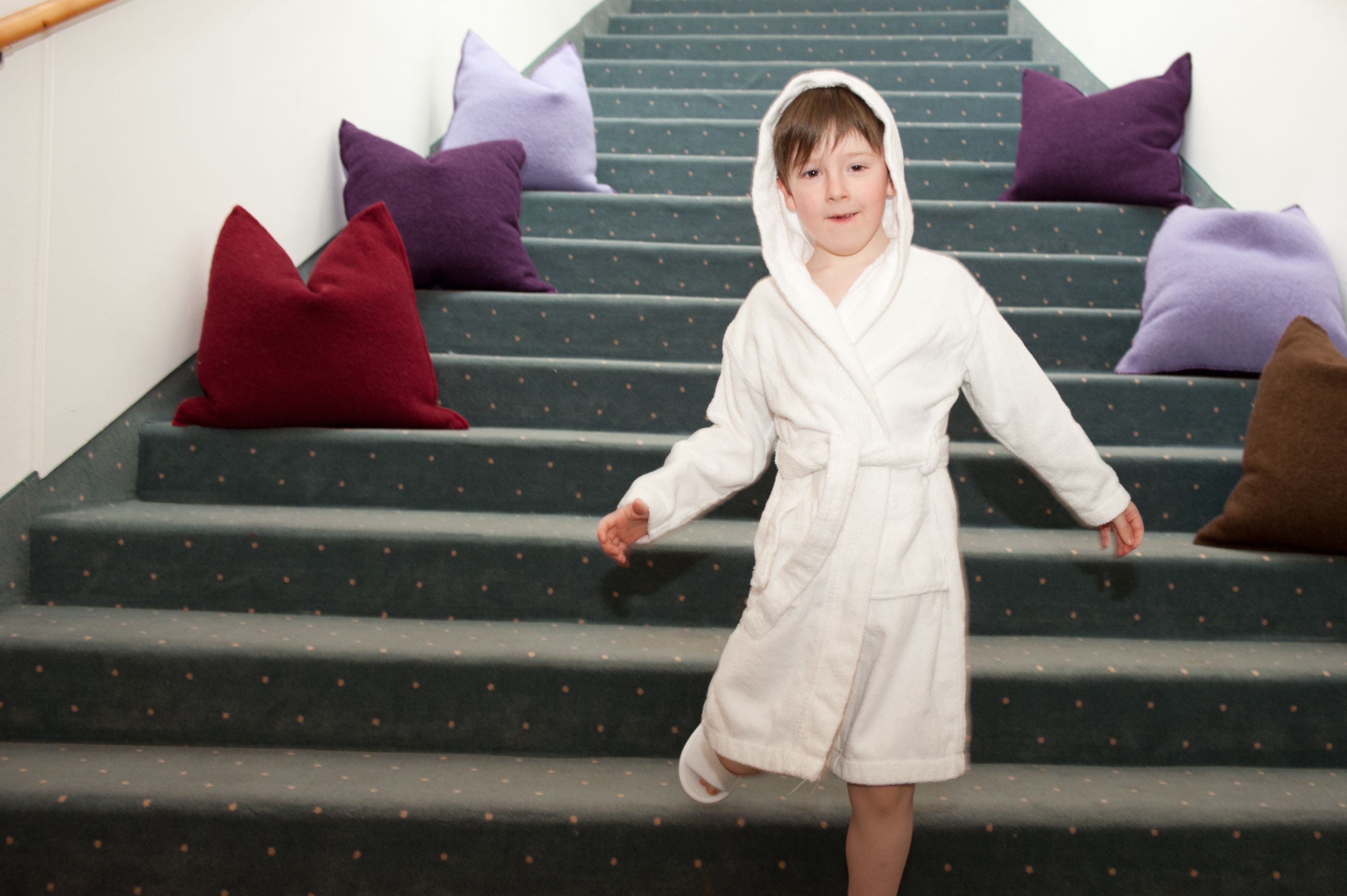 A person in a white robe descending a staircase with purple and red cushions.