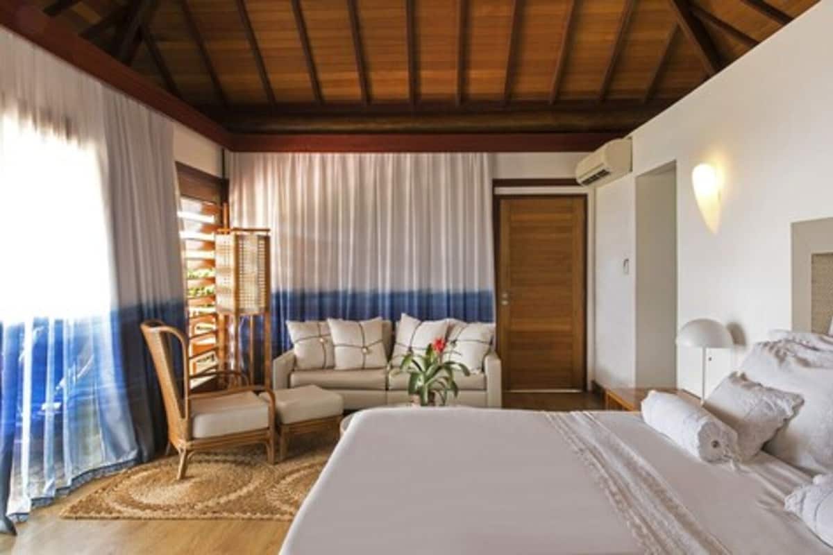 Un dormitorio con una cama grande, un sofá, una silla y techo de madera.