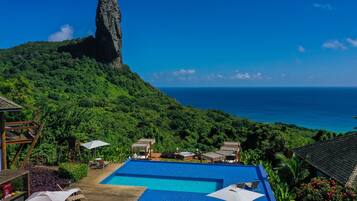 Relax by the infinity pool overlooking the ocean and distinctive rock formation.