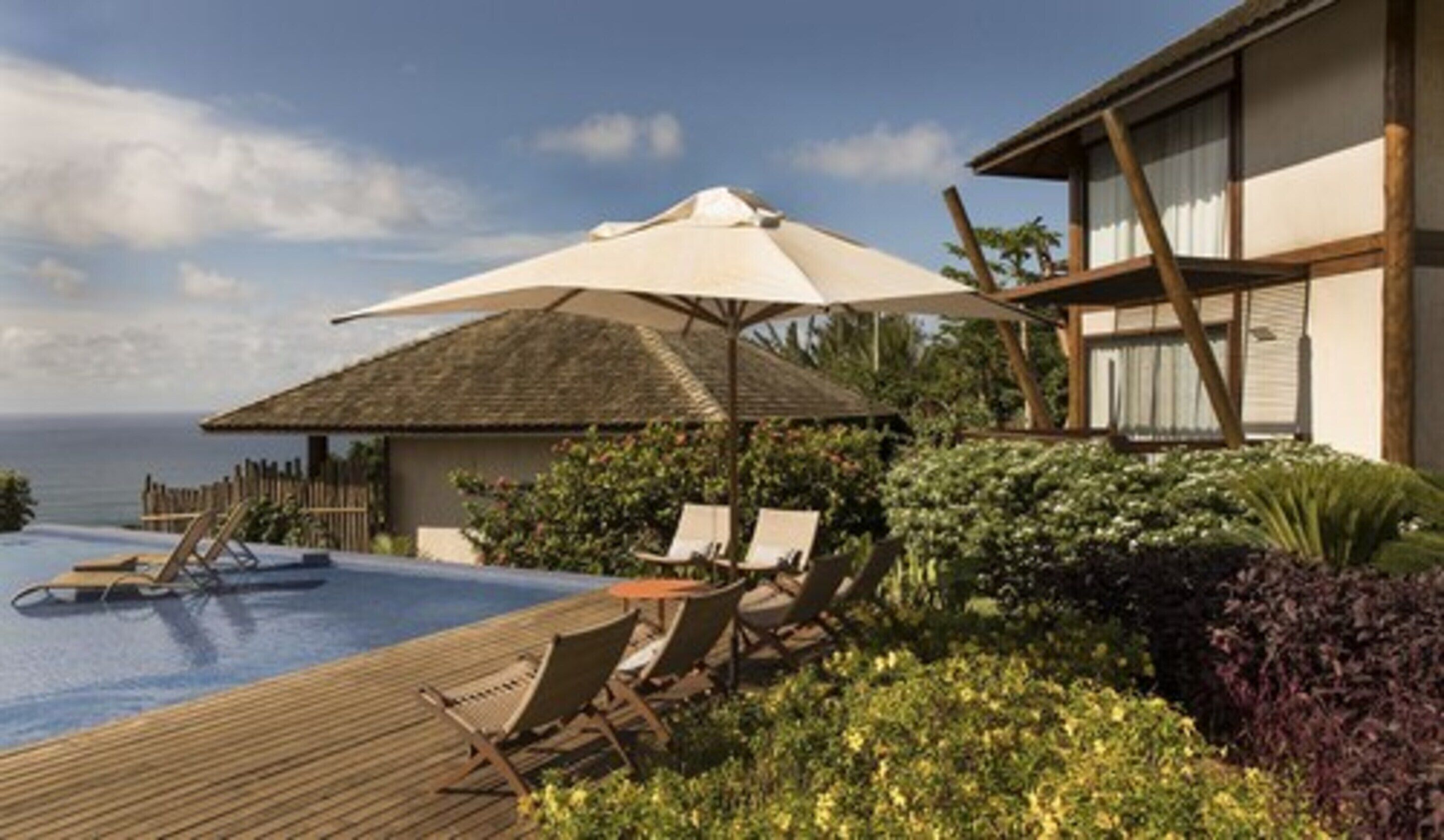 Un espace piscine avec des chaises longues et des parasols, une terrasse en bois et une vue sur la mer.