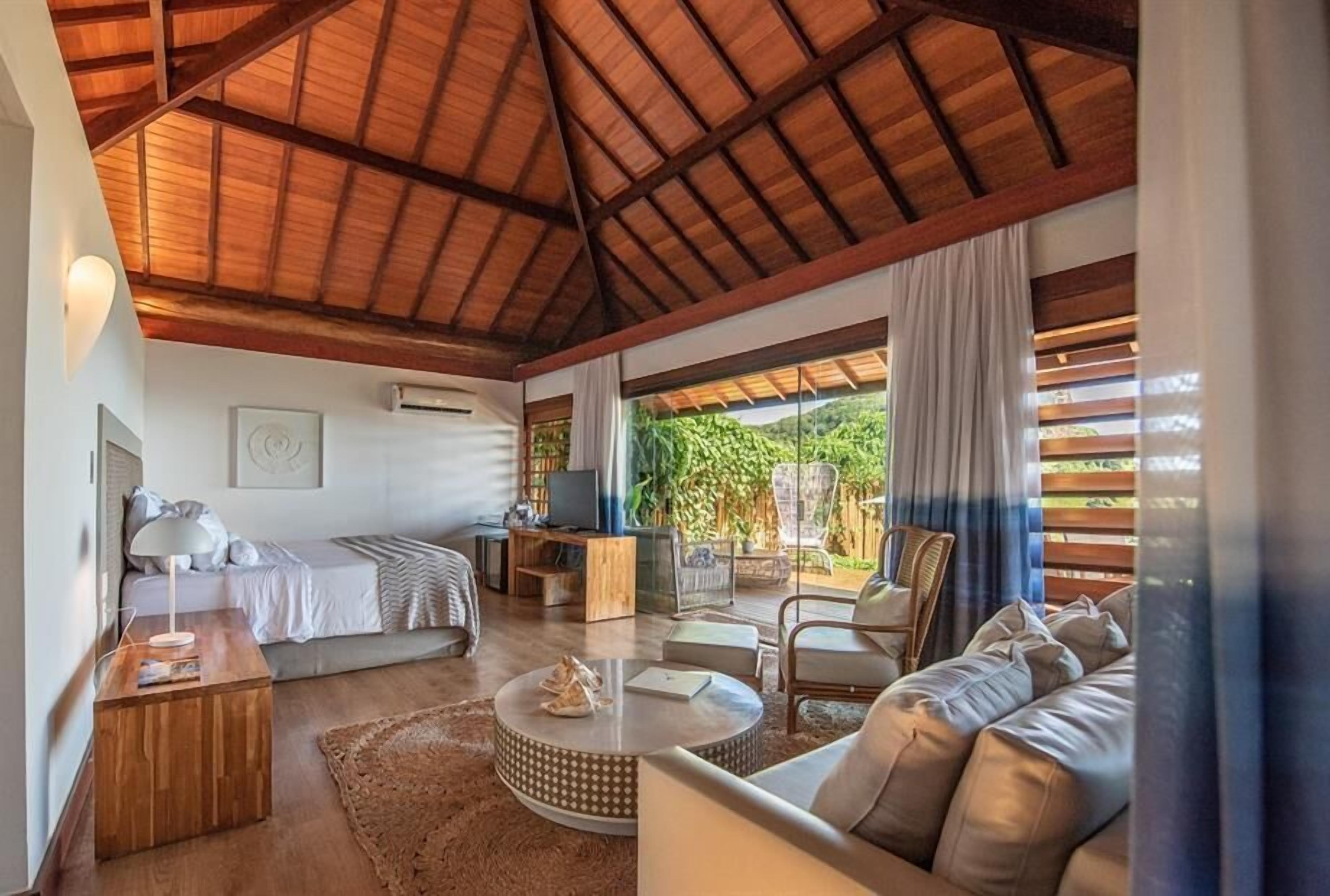 A spacious living area with a high ceiling, a bed, a sofa, a coffee table, and a TV.