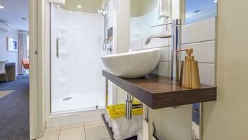 A modern bathroom with a glass-enclosed shower, a white sink, and a wooden vanity.
