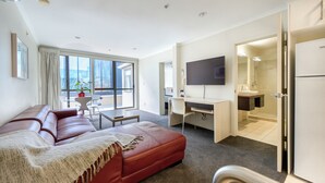 A modern hotel room with a red leather sofa, a desk with a computer, a flat-screen TV, and a bathroom visible through an open door. - U Residence Hotel, Signature Collection by BW (Wellington)