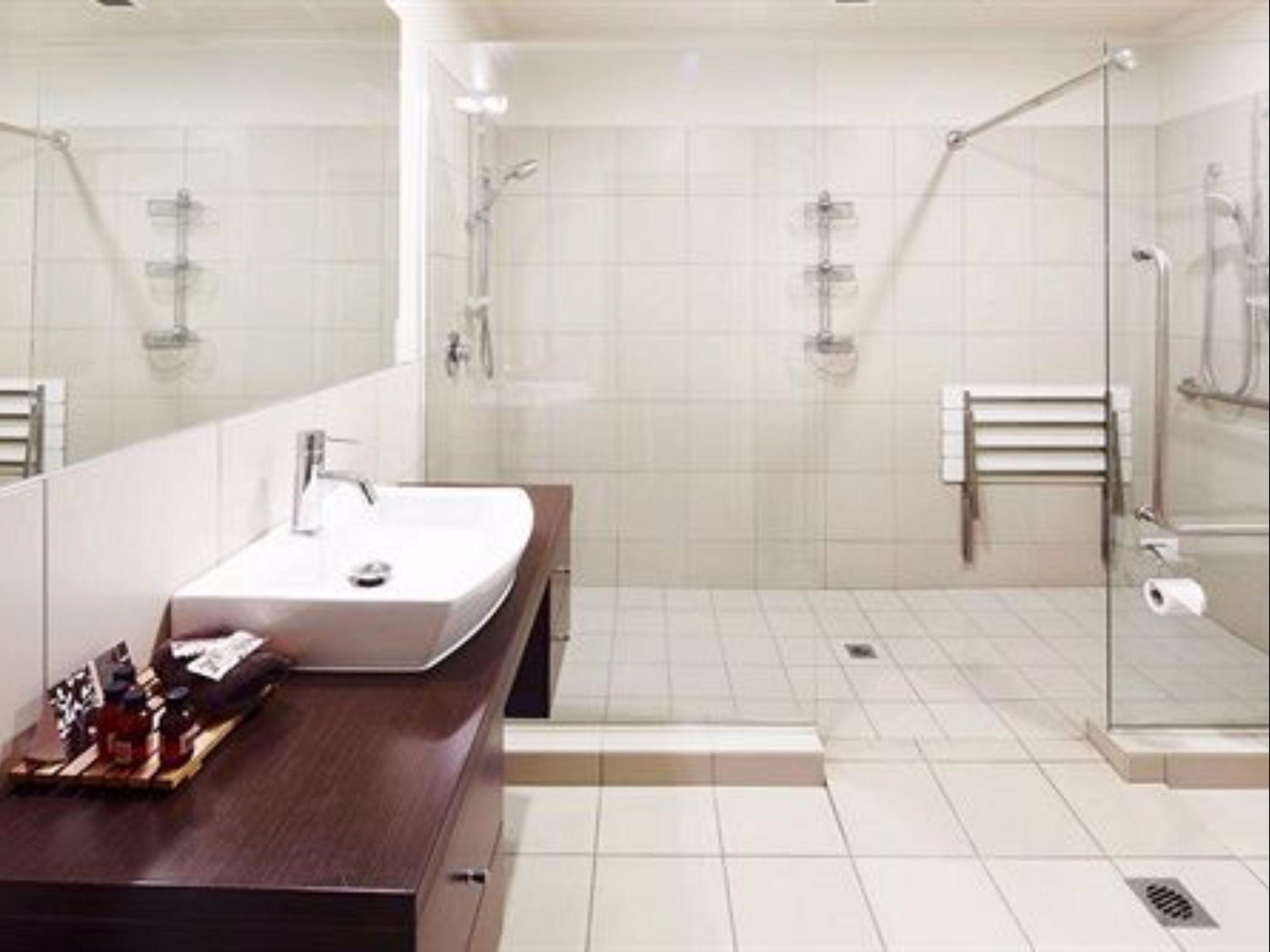 Une salle de bain moderne avec un grand miroir, un lavabo et un espace douche.