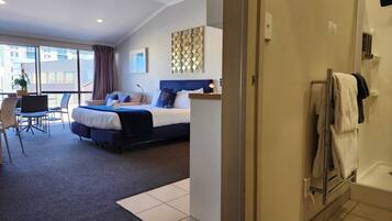 A hotel room with a bed, a desk, and a view of the city.