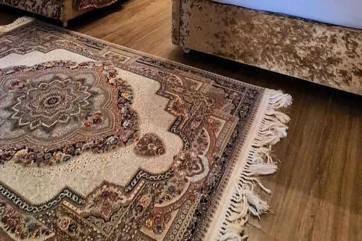 A hotel room with two beds, a chandelier, a large tapestry, and a patterned rug.