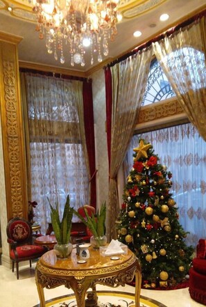 Una habitación lujosa con un gran árbol de Navidad, muebles ornamentados y una araña.