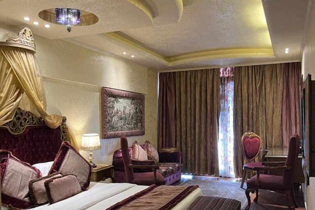 A hotel room with a large bed, a desk, a chair, and a painting on the wall.