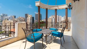 A rooftop terrace with a table and chairs, a pergola, and a city view. - Q Hotel (Beirut)
