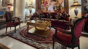 A luxurious living room with a red sofa, a gold coffee table, and a mural of cherubs on the ceiling. - Q Hotel (Beirut)