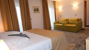 A hotel room with a bed, two armchairs, a carpeted floor, and wall-mounted lights. - Flores (Porec)