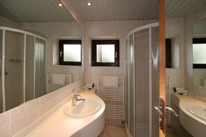 A modern bathroom with two sinks, a large mirror, and a shower area.