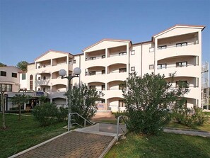 A multi-story hotel with balconies, a paved entrance, and surrounding greenery.