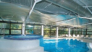 An indoor swimming pool with a hot tub and lounge area, surrounded by large windows. - Flores (Porec)
