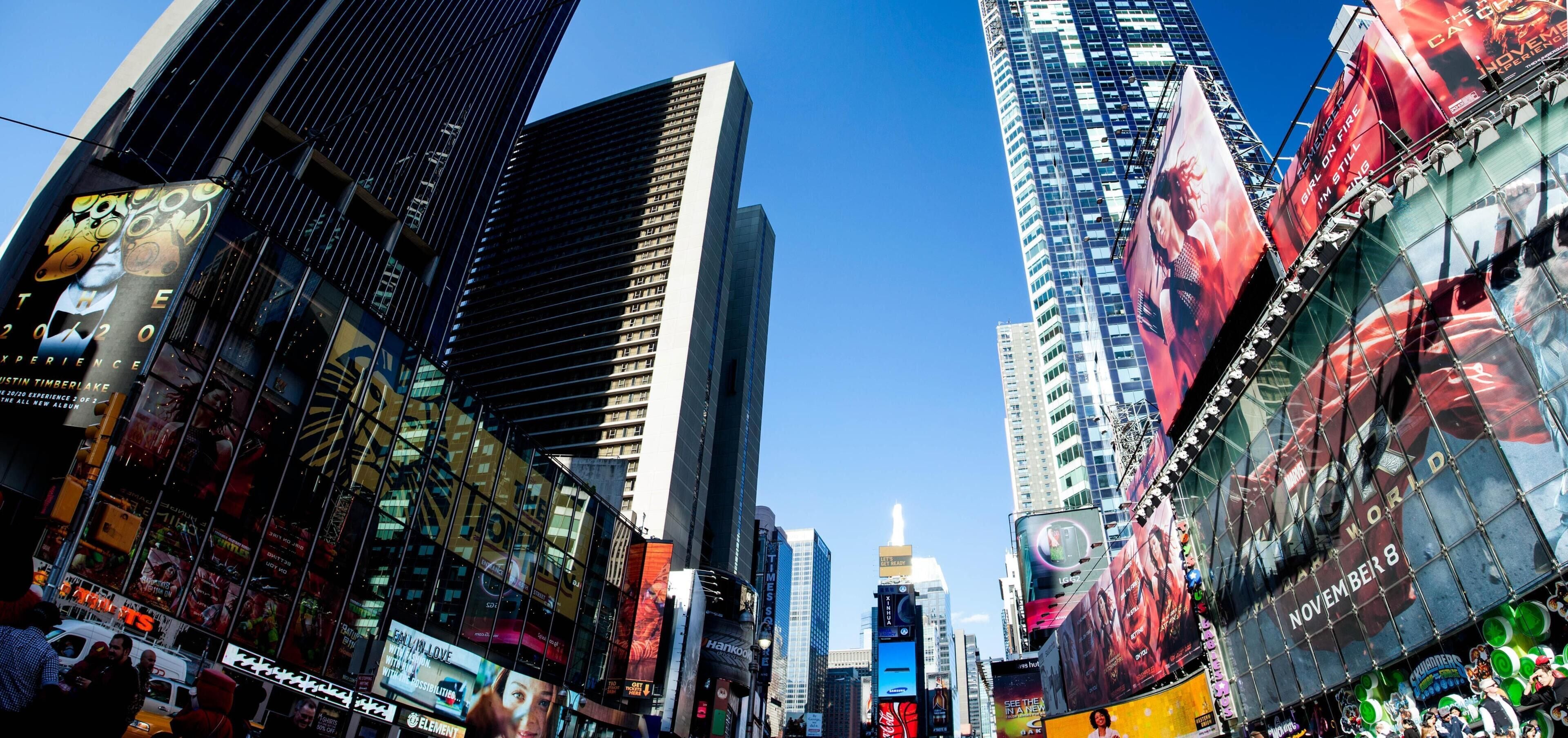 A cityscape with tall buildings and large billboards.