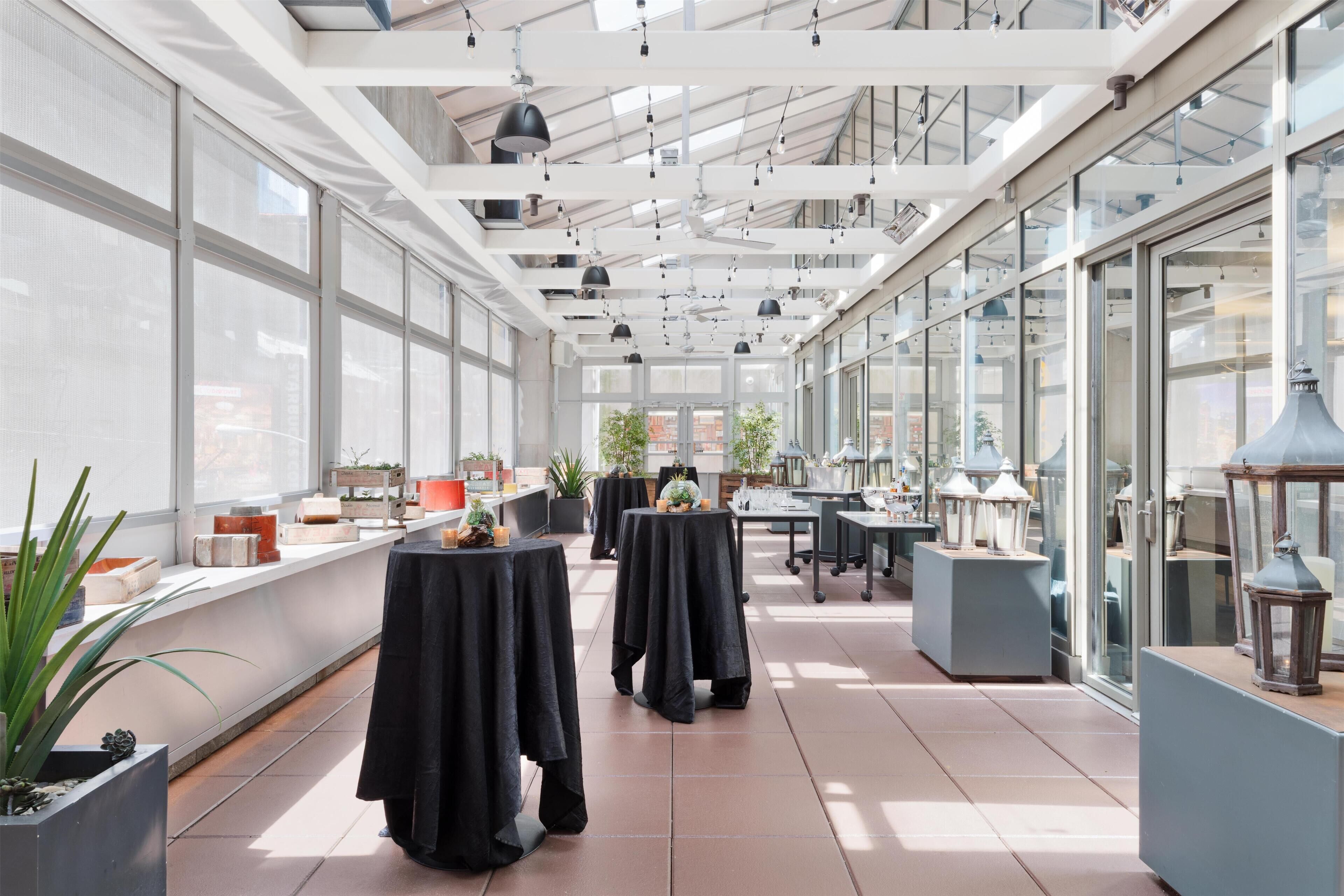 Un vaste espace intérieur aménagé avec des tables et des chaises, de grandes fenêtres et des ventilateurs de plafond.