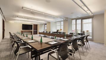 A conference room with long tables, chairs, a flat-screen TV, and large windows.