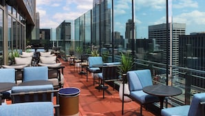 A rooftop terrace with outdoor seating, large windows, and a city skyline view. - Hyatt Centric Times Square New York (New York)