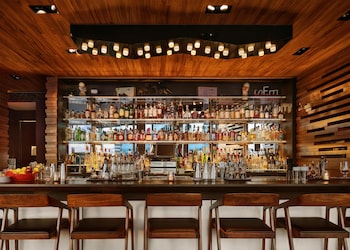 A modern hotel lobby with a curved reception desk, glass elevator, and a seating area with a coffee machine. at Hyatt Centric Times Square New York