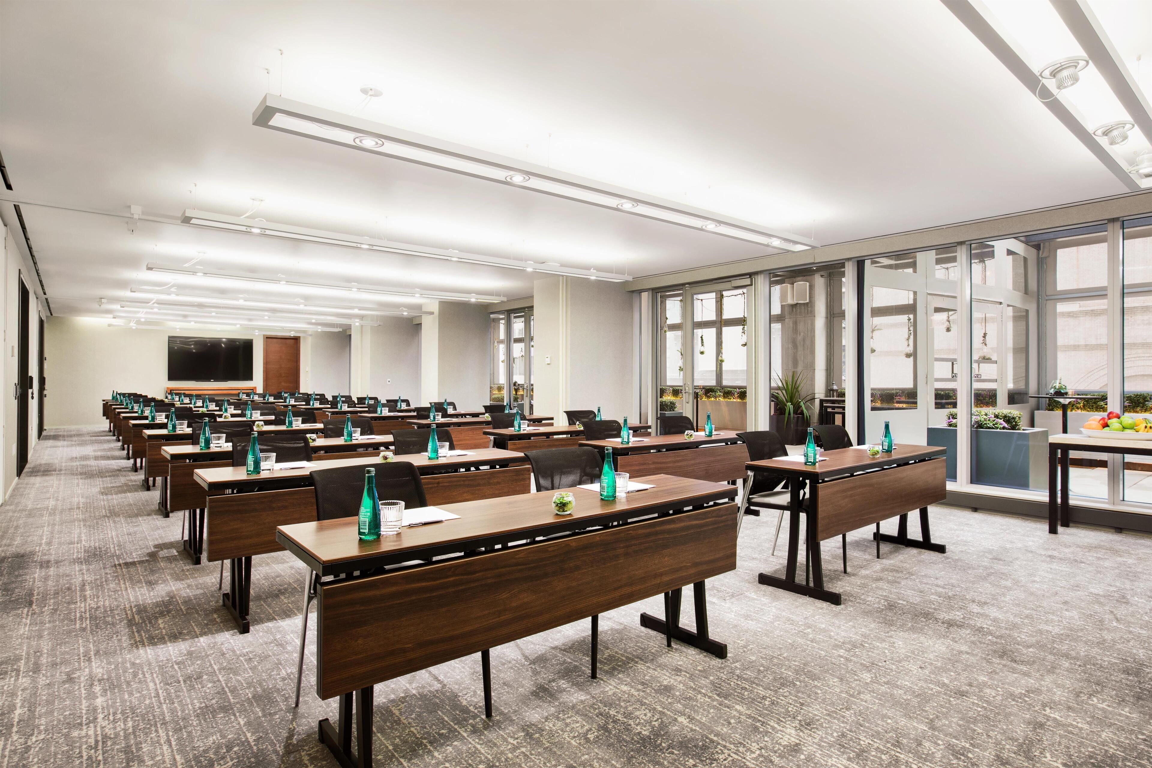 A conference room with long tables, chairs, and a large window.