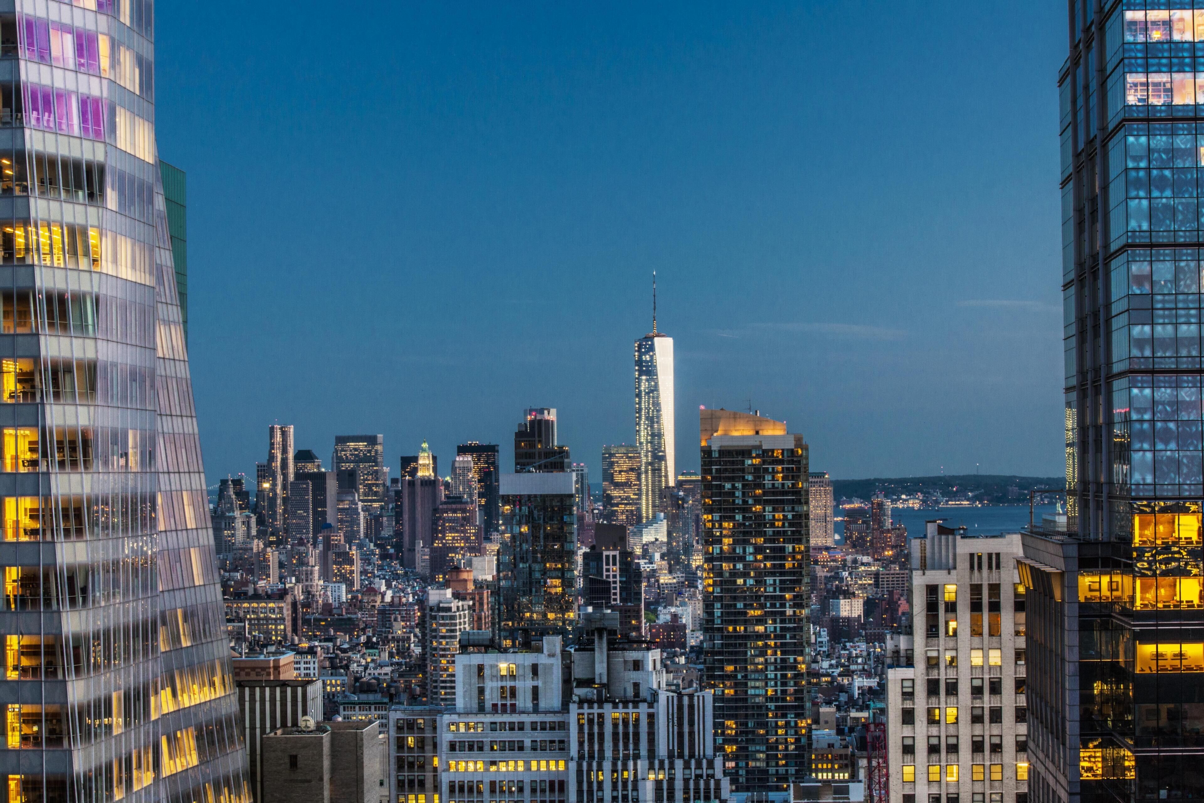 A cityscape with high-rise buildings, including a prominent skyscraper with a spire.