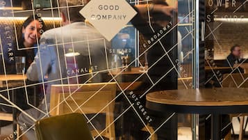 A restaurant with a modern interior, including a glass partition with street names and a sign reading 'GOOD COMPANY.'