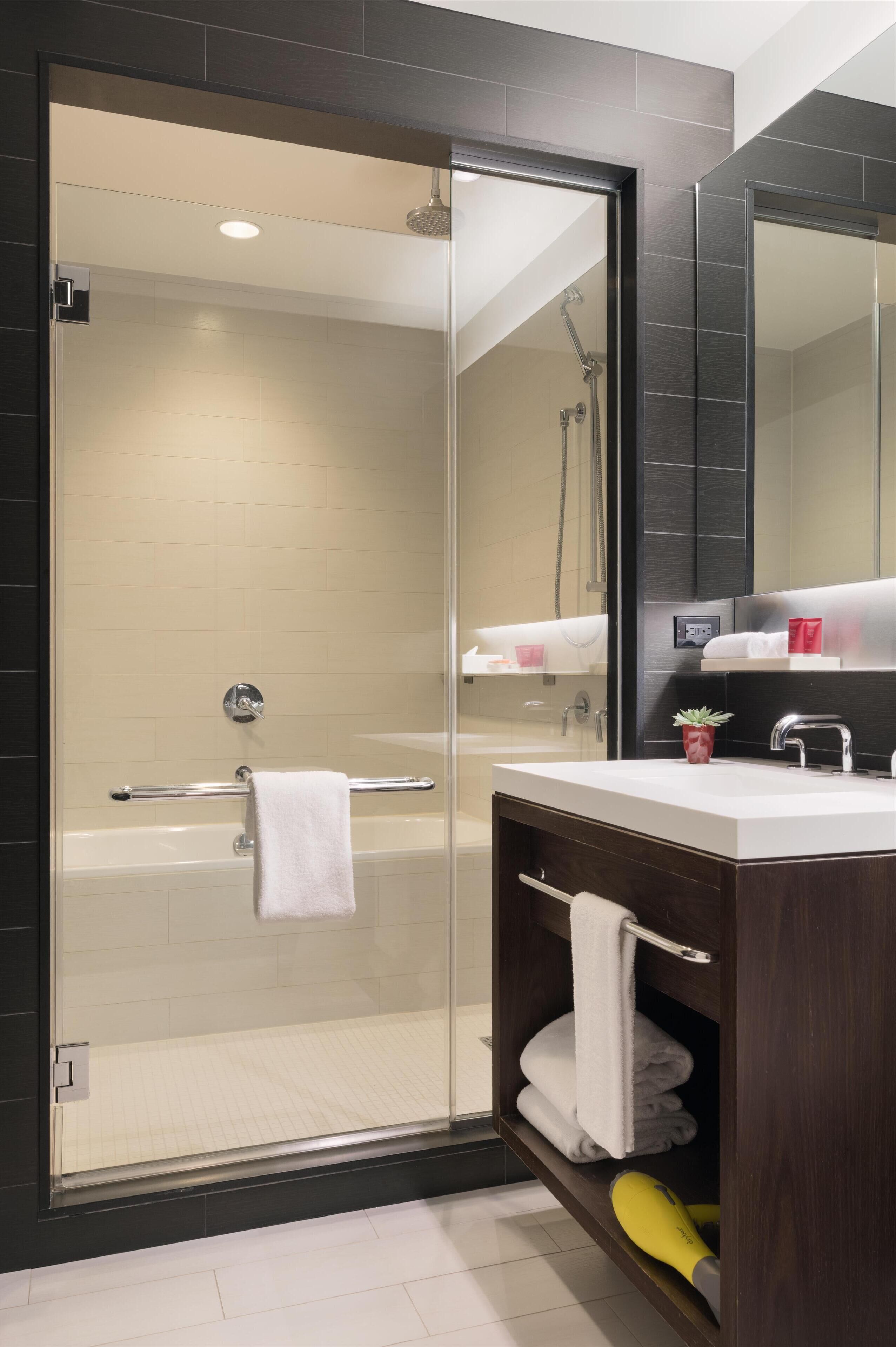 Une salle de bain moderne avec une douche à parois de verre, un meuble-lavabo avec un miroir et un porte-serviettes.