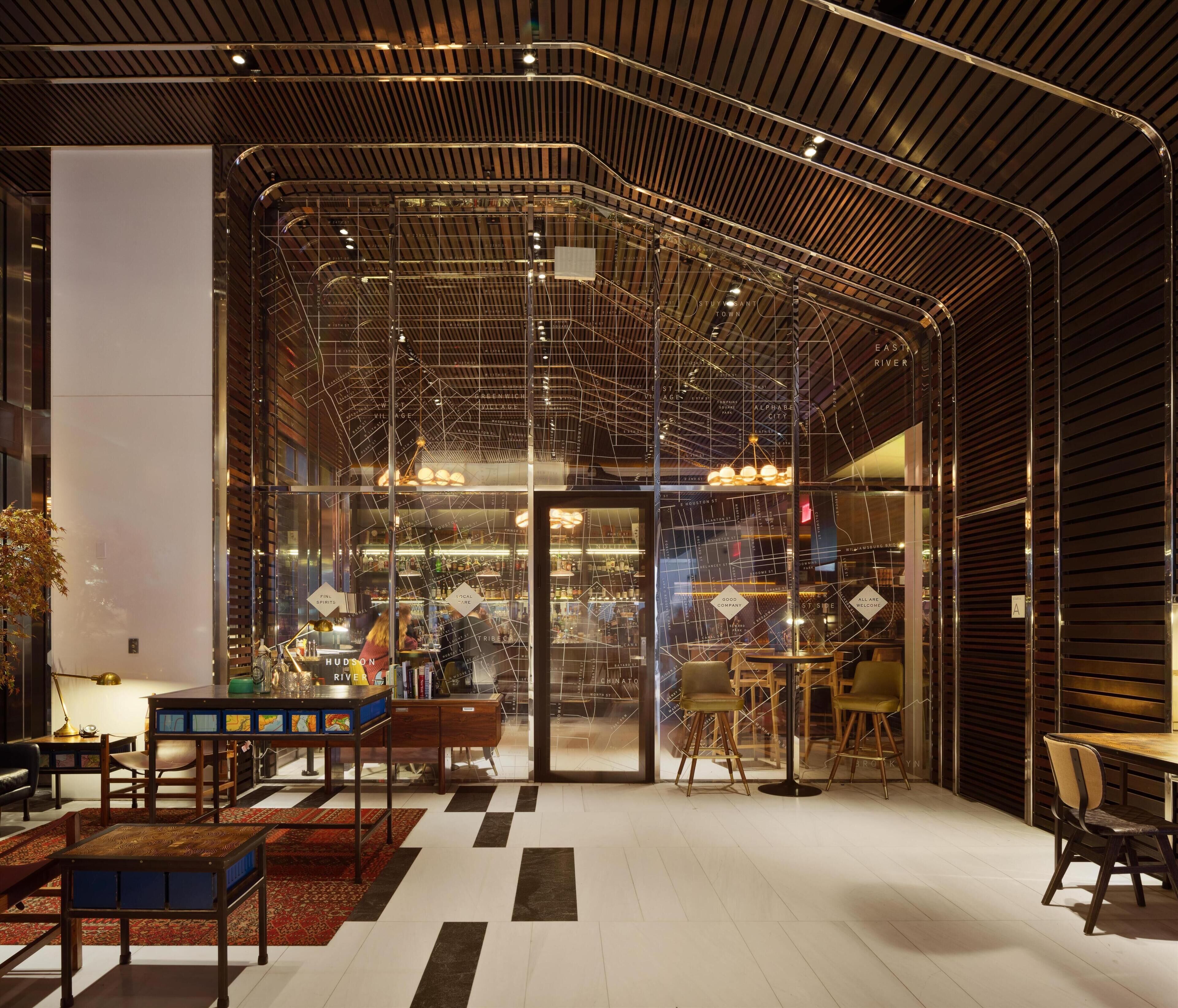 Un interior moderno con pared de vidrio, suelo de madera y estructura de techo metálica.